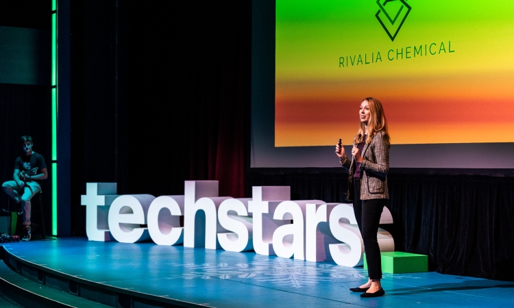 A woman on stage in front of large letters that spell "techstars"