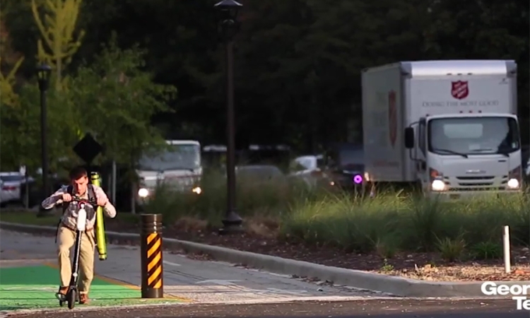 Screenshot of North Avenue Smart Corridor: One Year Later video, with student riding a scooter on separated bike path and traffic in vehicle lanes.