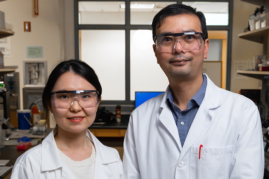 A man and woman wearing lab coats and goggles